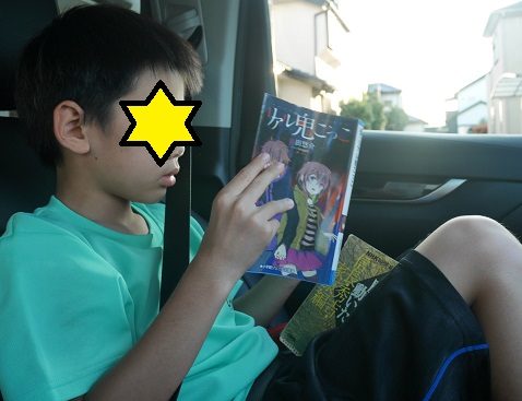 車の中でリアル鬼ごっこを読んでいる小学生の男の子