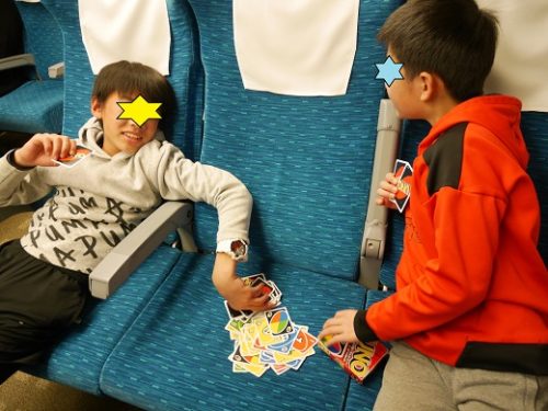 新幹線の中でUNOで遊ぶ小学生の男の子