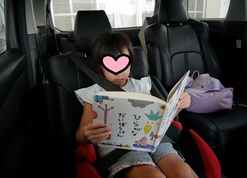 車の中で「ひらがなだいぼうけん」を読む小学1年生の女の子