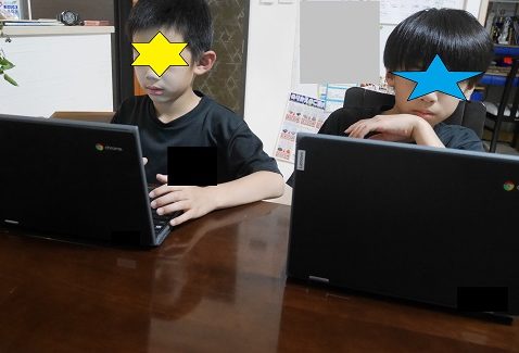 小学校から支給されたタブレットパソコンで宿題をする兄弟