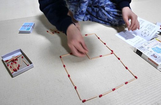 マッチ棒パズルで遊んでいる小学生の男の子
