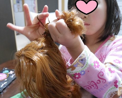 メガハウスのヘアメイクアーティストの人形の髪の毛を結んでいるところ