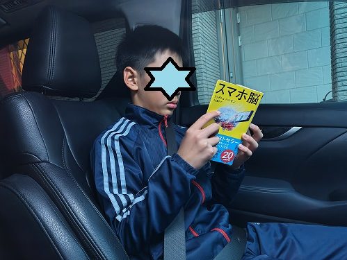 車の中で「スマホ脳」を読む小学6年生の男の子