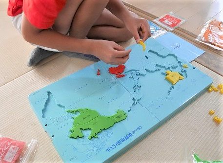 くもんの世界地図パズルで遊んでいる中学生と小学生の男の子