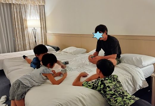 ホテルのベッドの上でトランプで遊んでいる家族